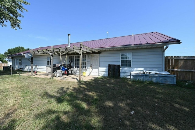 rear view of house featuring metal roof, fence, a yard, a standing seam roof, and a patio area