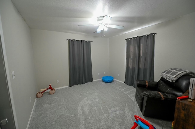 living area with carpet, baseboards, ceiling fan, and a textured ceiling