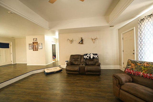 living area featuring a tray ceiling, ceiling fan, baseboards, and wood finished floors