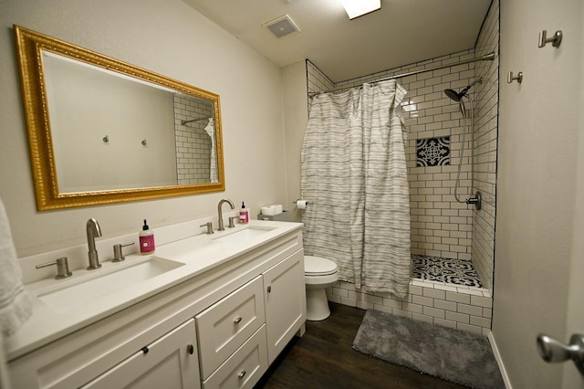 full bath featuring toilet, visible vents, a tile shower, and a sink