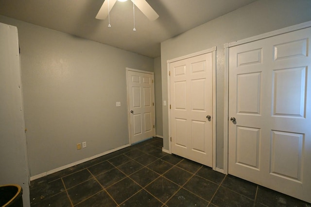 unfurnished bedroom with baseboards, a ceiling fan, and dark tile patterned flooring