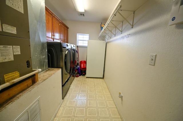 washroom featuring cabinet space, visible vents, light floors, and washing machine and clothes dryer