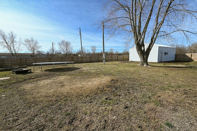 view of yard featuring an outbuilding, a trampoline, and a fenced backyard