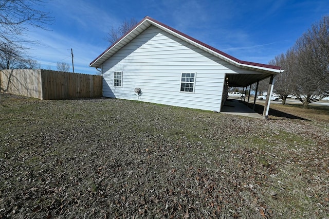 view of home's exterior featuring an attached carport and fence