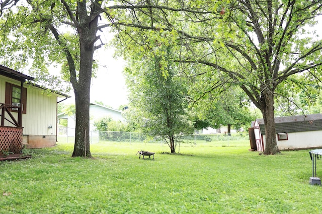 view of yard with fence, an outdoor structure, and a shed