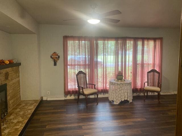 living area with ceiling fan, a fireplace, dark hardwood / wood-style floors, and plenty of natural light