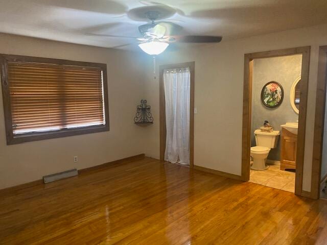 unfurnished bedroom featuring ceiling fan, connected bathroom, and hardwood / wood-style floors