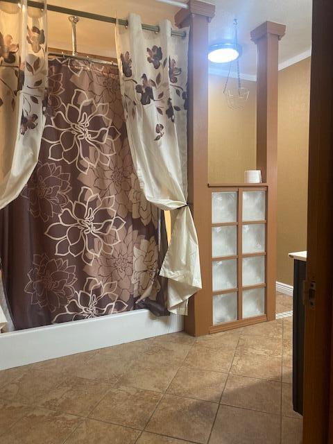 bathroom featuring tile patterned flooring, crown molding, decorative columns, shower / bath combination with curtain, and vanity