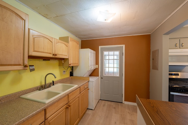 kitchen featuring stainless steel range oven, sink, ornamental molding, light hardwood / wood-style flooring, and stacked washer and clothes dryer