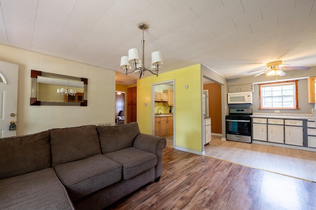 living room with ceiling fan with notable chandelier, hardwood / wood-style flooring, and sink