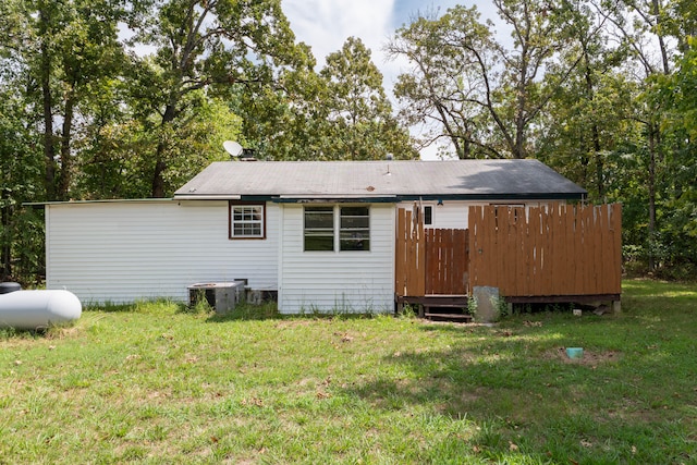 back of property with central AC unit and a lawn