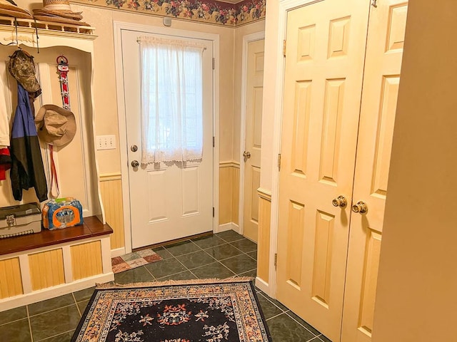 doorway to outside featuring baseboards and dark tile patterned flooring