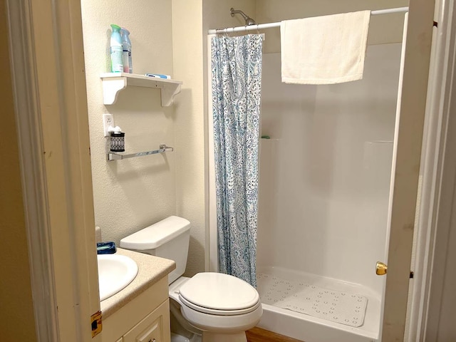 full bathroom featuring toilet, a textured wall, vanity, and a stall shower