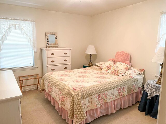 bedroom featuring light carpet and baseboards