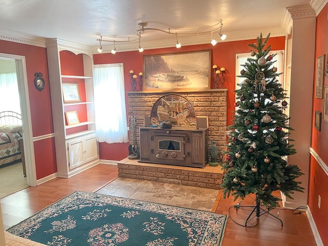living area with baseboards, ornamental molding, and wood finished floors