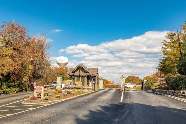 view of road featuring traffic signs, a gated entry, and curbs