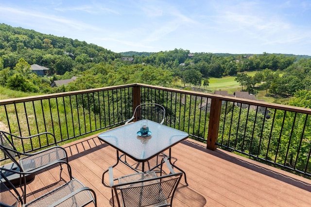 wooden terrace with a forest view and outdoor dining space