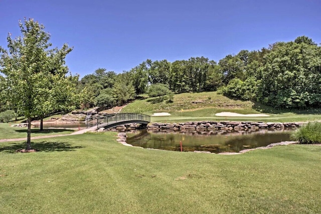 view of home's community with view of golf course, a yard, and a water view