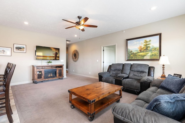 living room featuring ceiling fan, baseboards, a glass covered fireplace, and recessed lighting