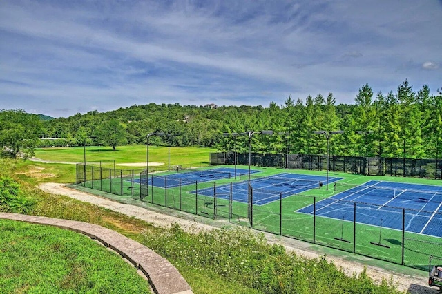 view of tennis court featuring a lawn and fence