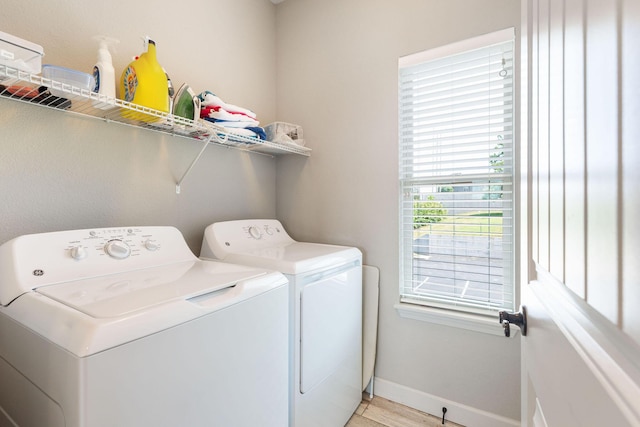 washroom featuring light wood finished floors, baseboards, washer and dryer, and laundry area