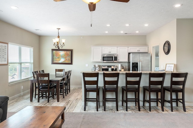 kitchen featuring white cabinets, stainless steel appliances, baseboards, and a kitchen bar
