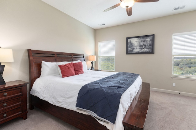 bedroom with ceiling fan, light colored carpet, and multiple windows