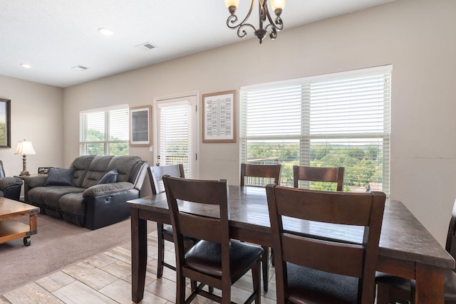 dining room with light colored carpet and a chandelier