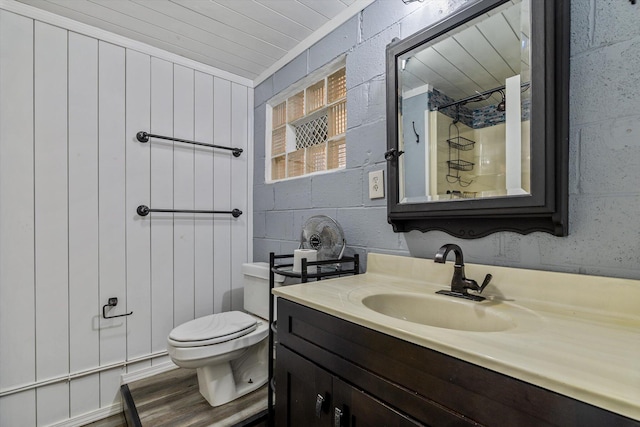 bathroom with wood walls, a shower, toilet, hardwood / wood-style flooring, and vanity