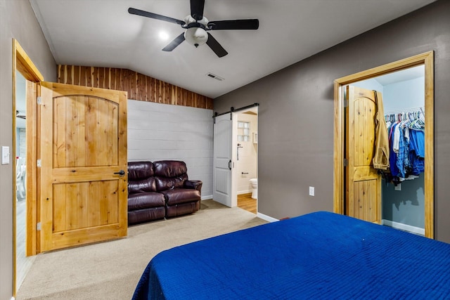 bedroom featuring lofted ceiling, ceiling fan, a closet, ensuite bath, and a barn door