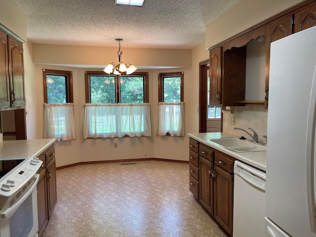 kitchen with hanging light fixtures, a healthy amount of sunlight, white appliances, and sink