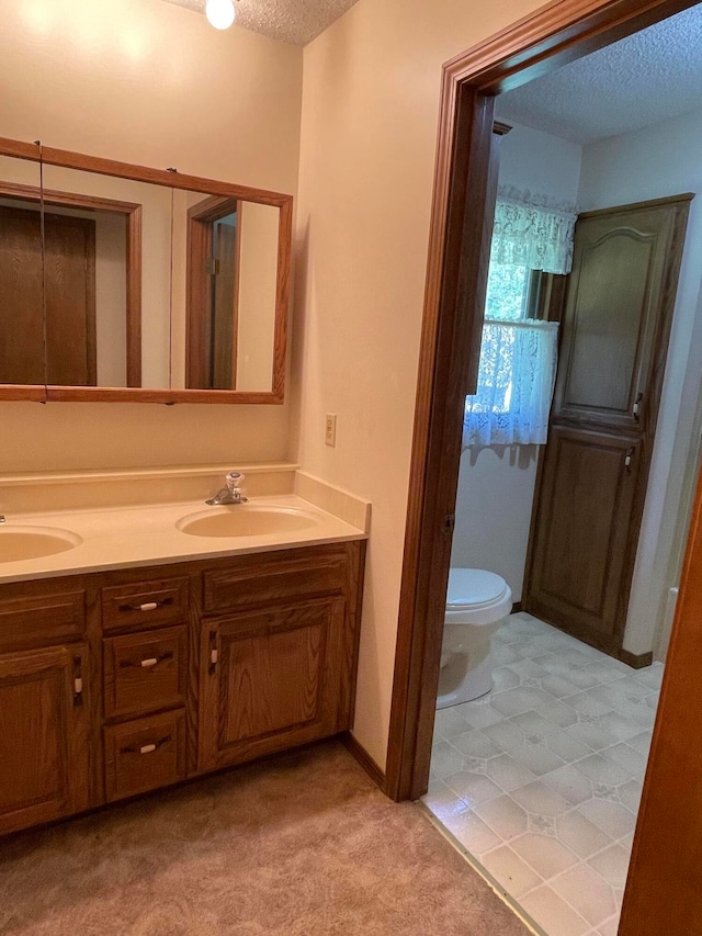 bathroom featuring a textured ceiling, vanity, and toilet