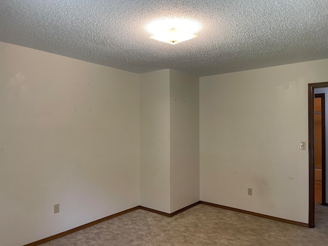 unfurnished room featuring light carpet and a textured ceiling