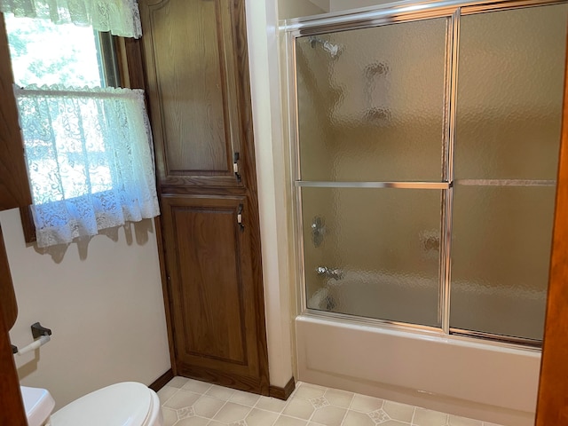 bathroom with bath / shower combo with glass door and toilet