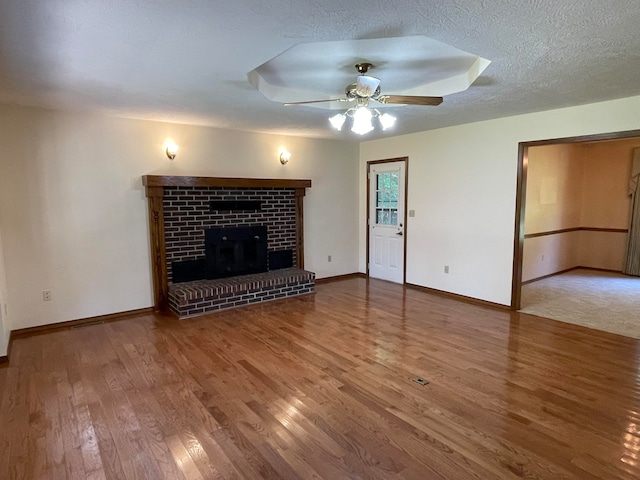 unfurnished living room with ceiling fan, hardwood / wood-style flooring, a fireplace, and a textured ceiling