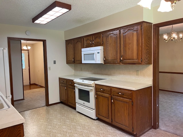 kitchen featuring white appliances, decorative light fixtures, and a textured ceiling