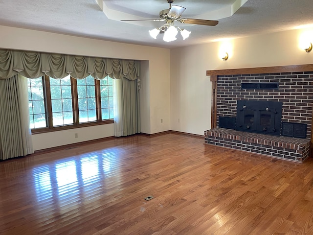 unfurnished living room with a fireplace, ceiling fan, hardwood / wood-style floors, and a textured ceiling