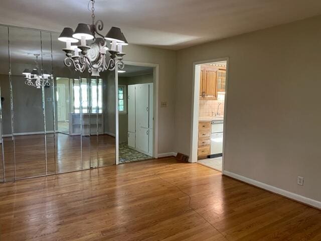 unfurnished dining area with an inviting chandelier and hardwood / wood-style flooring