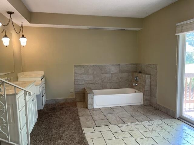 bathroom with vanity, a tub to relax in, a notable chandelier, and tile patterned floors