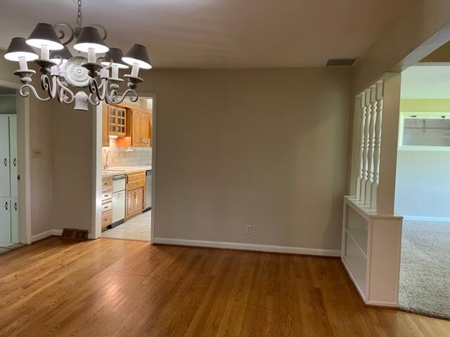 unfurnished dining area featuring sink, light hardwood / wood-style flooring, and a chandelier