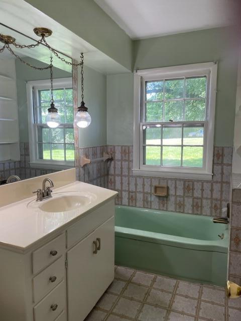 bathroom with vanity, a bathing tub, and tile walls