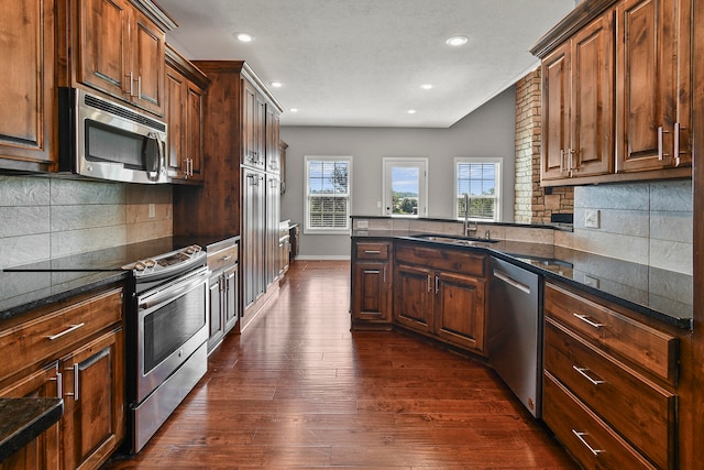 kitchen with appliances with stainless steel finishes, decorative backsplash, sink, and dark hardwood / wood-style flooring