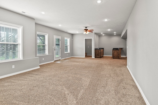 unfurnished living room featuring ceiling fan and light carpet