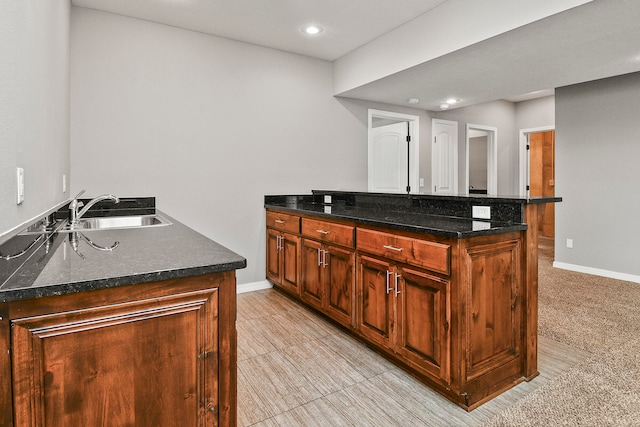 kitchen featuring dark stone countertops, sink, a center island, and light carpet