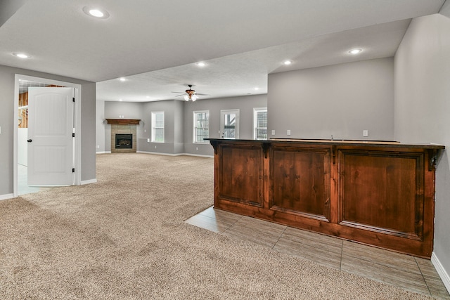 bar featuring light carpet, a textured ceiling, a fireplace, and ceiling fan