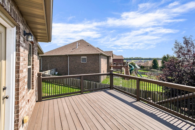 wooden deck with a playground and a lawn