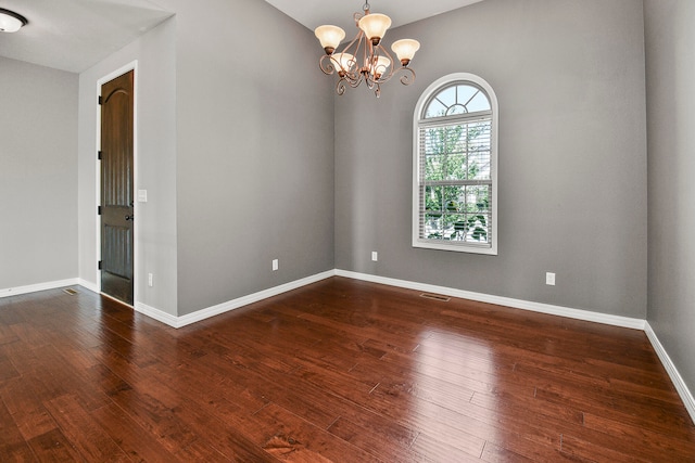 empty room with an inviting chandelier and dark hardwood / wood-style floors