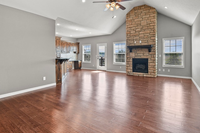 unfurnished living room featuring high vaulted ceiling, a healthy amount of sunlight, and dark hardwood / wood-style floors