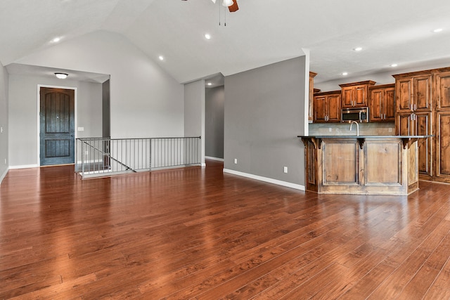 unfurnished living room with ceiling fan, vaulted ceiling, and dark hardwood / wood-style flooring