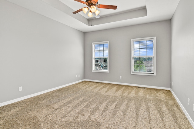 unfurnished room featuring ceiling fan, a tray ceiling, and carpet